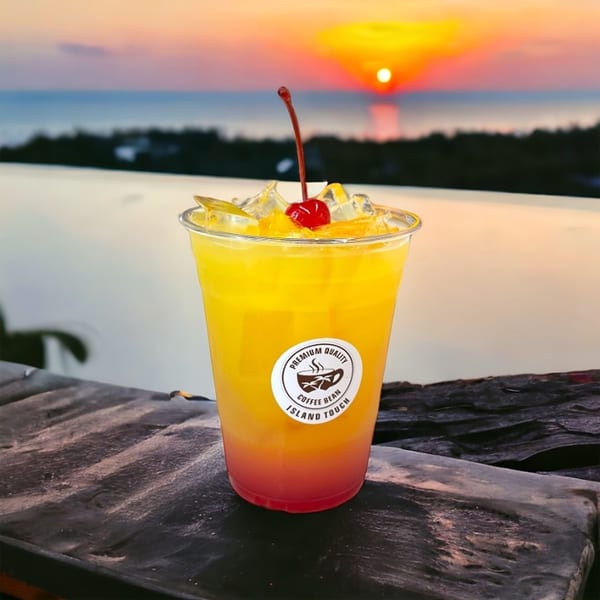 Tropical drink with a cherry and ice, set against a vibrant sunset over the ocean.